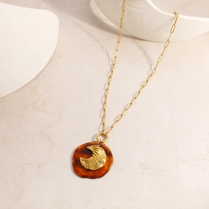 Détail du collier lune rétro avec résine ambre et relief doré aux motifs rayons de soleil