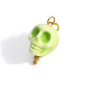 Detailed view of light green skull pendant with glazed finish and gold metal loop charm