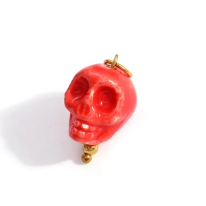 Macro shot of a red gothic skull charm with a glossy finish and gold metal accents