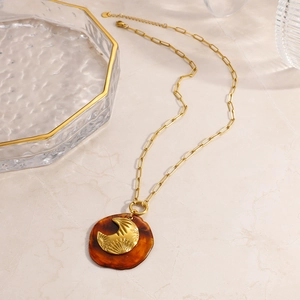 Collier en acier inoxydable doré avec pendentif lune sur un plateau en verre