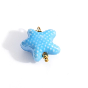 Detail of blue polka dot star ceramic pendant with gold eyelet for DIY jewelry