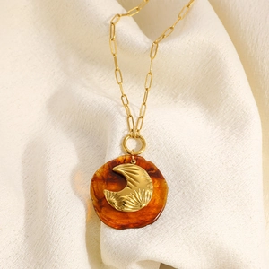 Vue détaillée du pendentif lune ambre sur une chaîne trombone dorée de style vintage