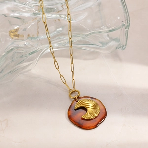 Détail du pendentif lune sur chaîne trombone avec base en résine de couleur ambre
