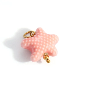Close-up of pink star pendant with white dots and gold beads for DIY jewelry making