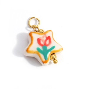 Macro detail of star-shaped ceramic pendant with painted tulip and gold metallic rings