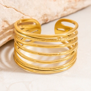 Détail d'une bague large multicouche en acier titane doré avec texture martelée
