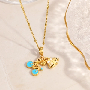 Detail view of gold bead chain with blue bicycle, white car, and solid heart charms