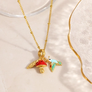 Detail of mushroom and hummingbird charms on gold chain with enamel finish