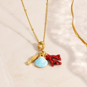 Detail of nautical pendant necklace with gold fish, blue shell, and red coral charms