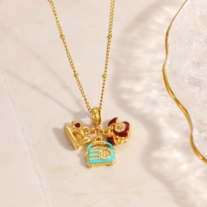 Macro shot of vintage sewing machine, radio and telephone charms on gold chain