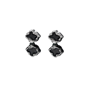 Irregular silver magnetic earrings with black enamel drip design on white background
