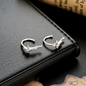 Silver butterfly ear cuffs with sparkling zircon stones on black leather background