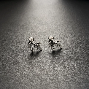Silver maple leaf stud earrings with vintage texture on a black leather background