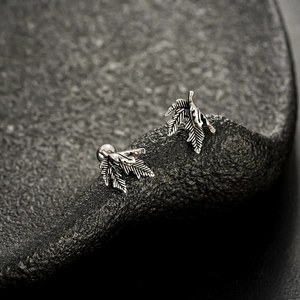 Detailed close-up of retro silver maple leaf earrings with intricate vein textures