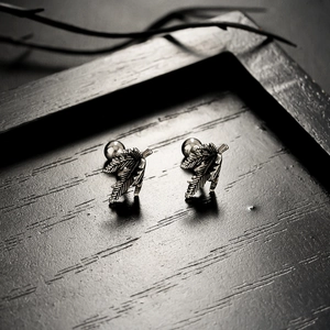 Detail view of silver maple leaf earrings with realistic textures on dark wood background
