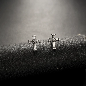 Vue macro des boucles d'oreilles croix vintage en argent avec texture de corde tressée