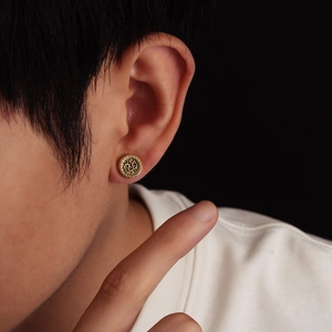Close-up of golden vintage earring with traditional dragon pattern on male model ear