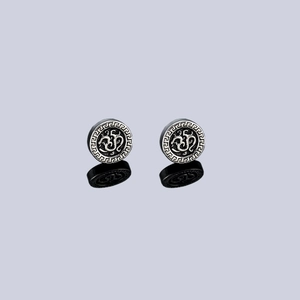 Macro detail of silver Greek Key pattern clip earrings with black base and dragon emblem