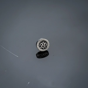 Macro shot of vintage silver stud earring with Om symbol and Greek fret pattern