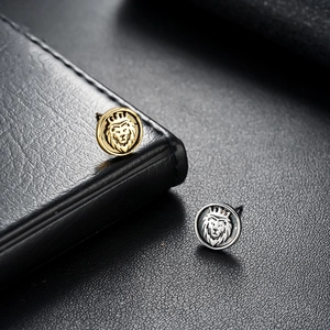Lion head earrings with crown in gold and silver finish on a black leather background