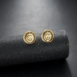 Macro view of gold-plated lion head earrings with crown relief on black stand