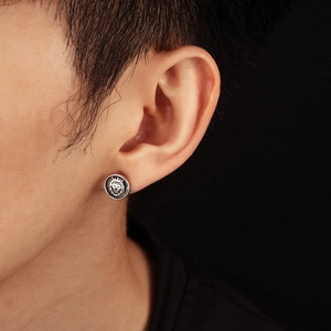 Macro detail of retro silver lion head stud earring with crown on male model