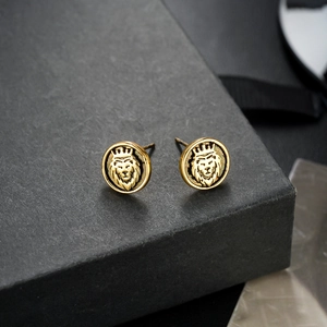 Vintage gold lion head stud earrings with crown relief on dark geometric display