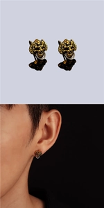 Gros plan sur des boucles d'oreilles dorées style masque avec anneau métallique