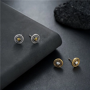 Macro view of vintage round Eye of Horus stud earrings in silver and gold steel