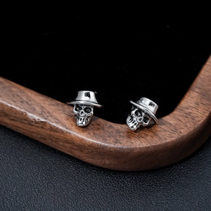 Pendientes de calavera punk de plata vintage con sombrero sobre terciopelo oscuro