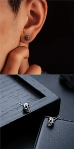 Detalle de pendientes de calavera de plata vintage sobre madera oscura y cuero fino