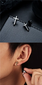 Détail de boucles d'oreilles croix en noir, blanc et or sur cuir et portées à l'oreille