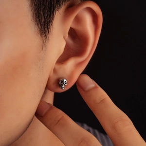 Pendientes de calavera gótica en plata antigua usados por modelo con fondo oscuro