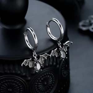 Macro detail of silver batman hoop earrings featuring faceted black gemstone and gothic wings