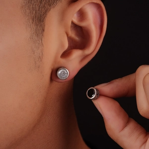Detail of round zircon studs with vintage engraved edges in silver and black colors