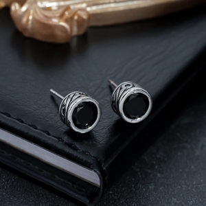 Close-up of black zircon stud earrings with intricate vintage engraved silver metal texture