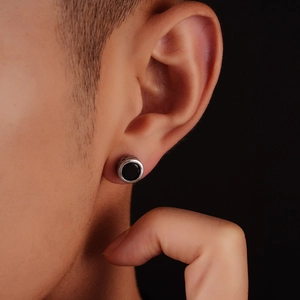 Close-up of a men's vintage silver stud earring with a black onyx-style inlay on ear