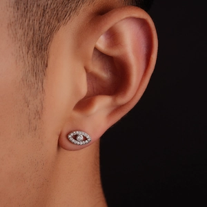 Macro shot of silver Evil Eye stud earring with pavé zircon setting on human ear