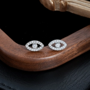 Macro shot of silver devil's eye stud earrings with detailed zircon inlay on wood stand