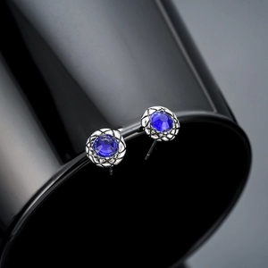 Macro view of blue zircon stud earrings with silver-toned textured engraving details