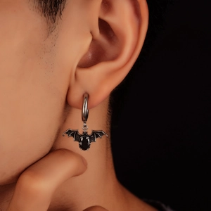 Macro shot of a silver hoop earring featuring a gothic black bat pendant with a dark gem