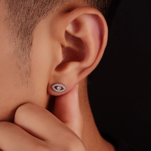 Mens fashion Evil Eye stud earrings with pavé crystals on a dark background
