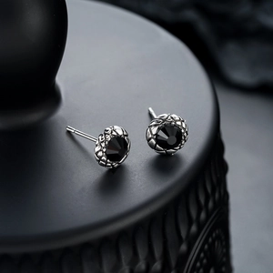 Macro detail of gothic silver stud earrings featuring black zircon and scale texture
