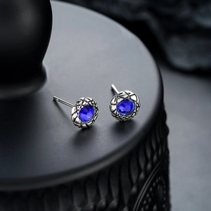 Blue zircon stud earrings with silver textured base for men and women on black stand