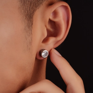 Macro shot of a men's silver earring with a large clear zircon and black engraved details