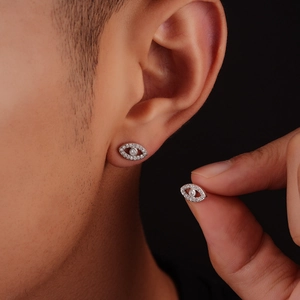 Close-up of a model wearing an evil eye stud earring with pavé diamonds and silver finish