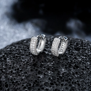 Vue macro de boucles d'oreilles huggies argentées serties de zircons sur pierre de lave