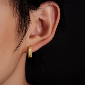 Gros plan de boucles d'oreilles créoles dorées serties de zircons sur l'oreille