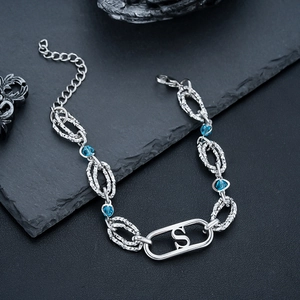 Gros plan détaillé d'un bracelet en argent avec cristaux bleus et pendentif lettre S central