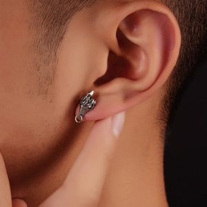Close-up of a silver polished hand gesture stud earring in punk street style